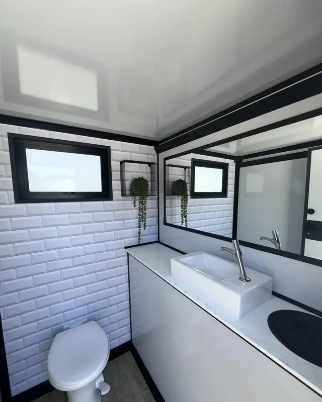 Tiled interior of a restroom trailer with sink and toilet