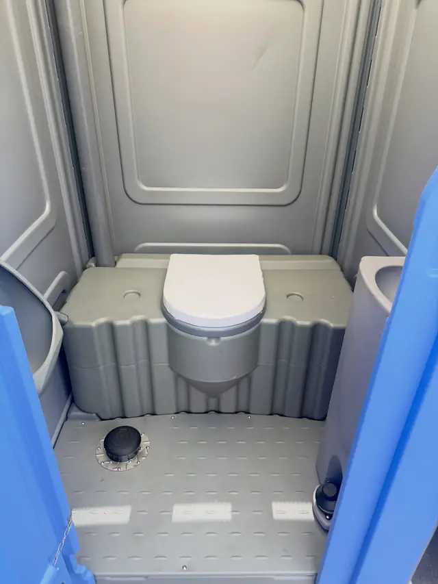 Gray interior of a standard porta potty with the seat lid closed